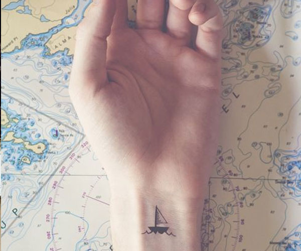 Sencillo tatuaje de un barco en la muñeca